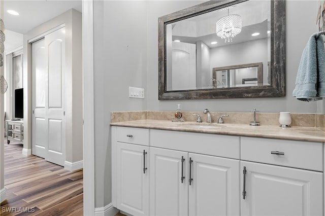 bathroom featuring recessed lighting, baseboards, wood finished floors, and vanity