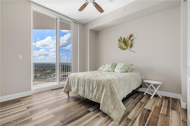 bedroom featuring baseboards, expansive windows, wood finish floors, and access to exterior