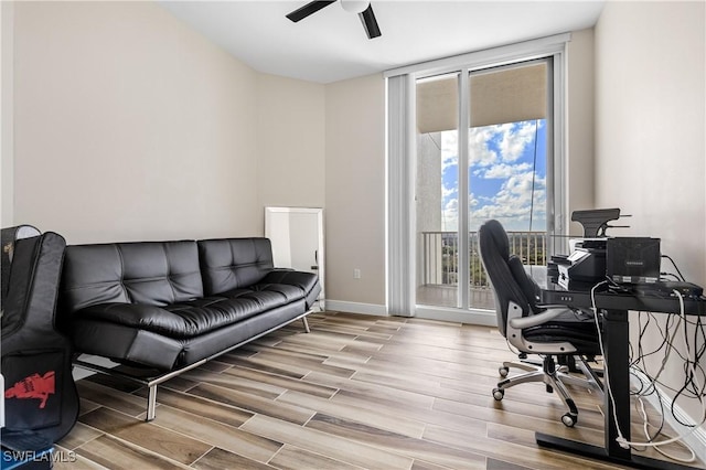 office space featuring wood tiled floor, expansive windows, baseboards, and ceiling fan