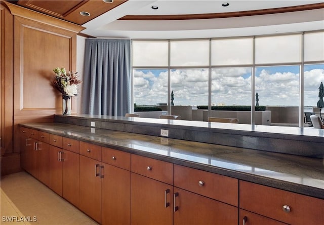 kitchen featuring plenty of natural light, dark stone counters, and brown cabinetry