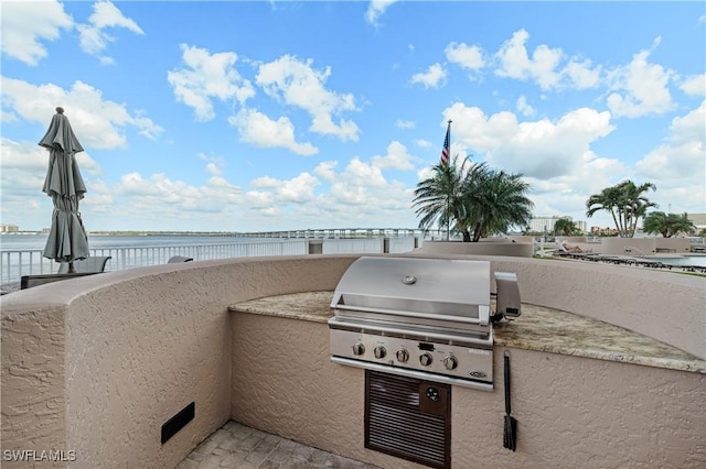 view of patio with area for grilling, an outdoor kitchen, and a water view