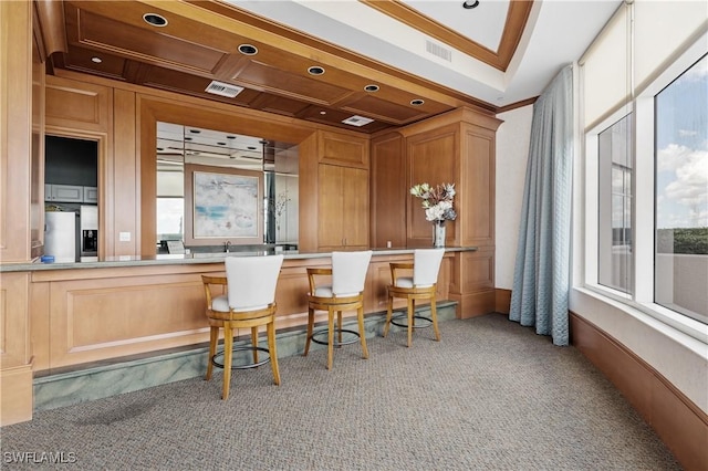 bar featuring stainless steel refrigerator with ice dispenser, light colored carpet, crown molding, and visible vents