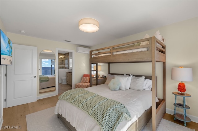 1 Sunset Captiva Ln, Captiva, FL 33924 - bedroom with wood finished floors, an AC wall unit, connected bathroom, and arched walkways