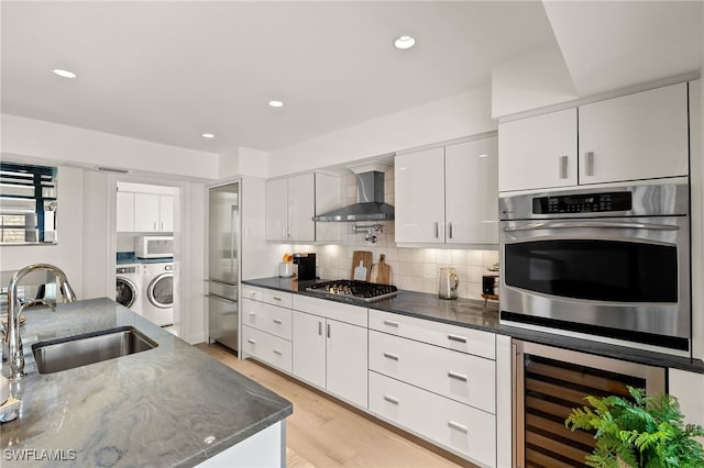 1 Sunset Captiva Ln, Captiva, FL 33924 - kitchen with wall chimney range hood, a sink, wine cooler, stainless steel appliances, and washing machine and clothes dryer
