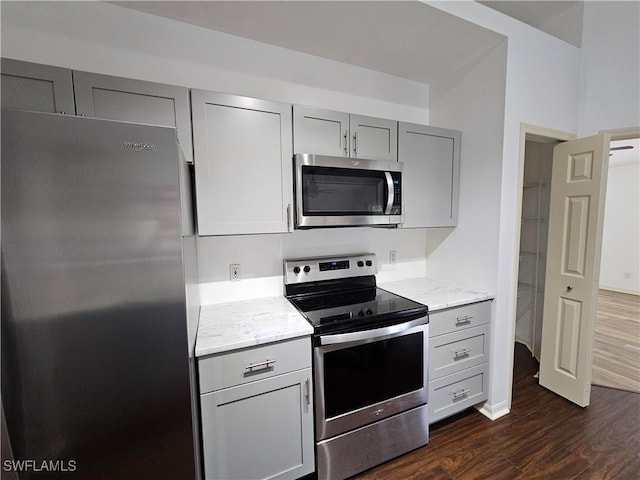 kitchen featuring light stone counters, stainless steel appliances, dark hardwood / wood-style floors, and gray cabinets