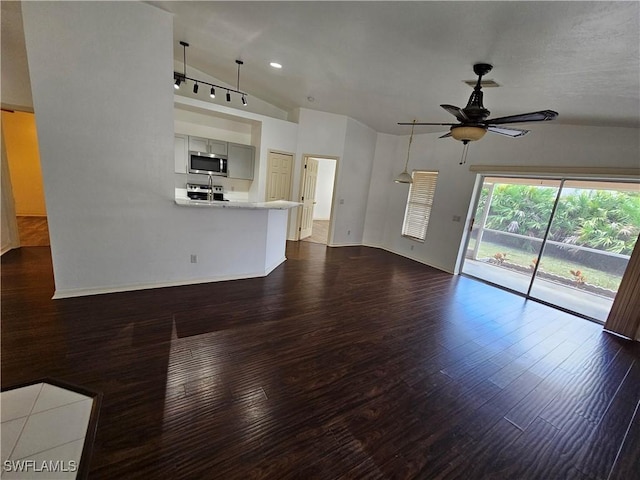 unfurnished living room featuring vaulted ceiling, dark hardwood / wood-style floors, and ceiling fan