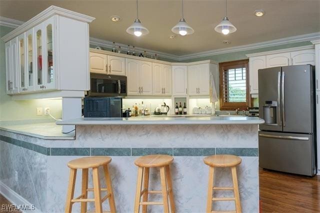 kitchen with white cabinetry, stainless steel appliances, a kitchen bar, and pendant lighting