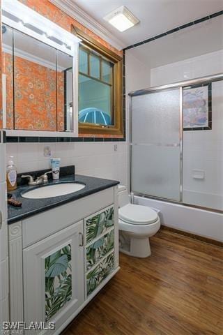 full bathroom with enclosed tub / shower combo, hardwood / wood-style floors, vanity, ornamental molding, and toilet