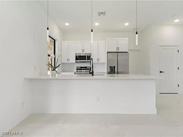 kitchen with white cabinetry, appliances with stainless steel finishes, decorative light fixtures, and sink