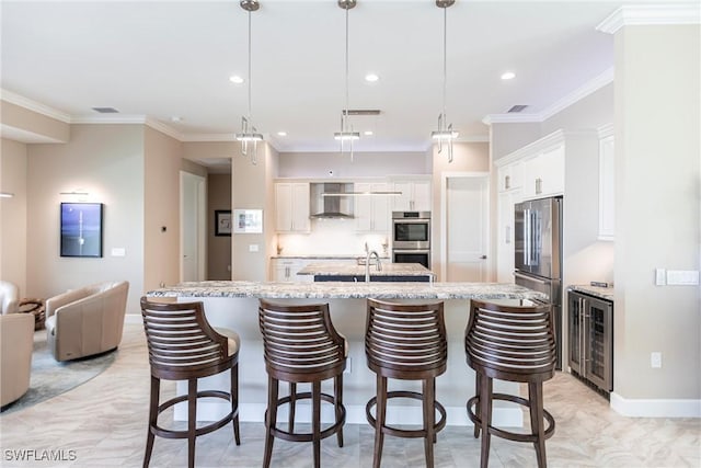 17122 Barcrest Ln, Punta Gorda, FL 33955 - kitchen with beverage cooler, wall chimney exhaust hood, appliances with stainless steel finishes, ornamental molding, and a kitchen island with sink