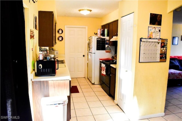 kitchen featuring black appliances, light tile patterned floors, light countertops, and dark brown cabinets