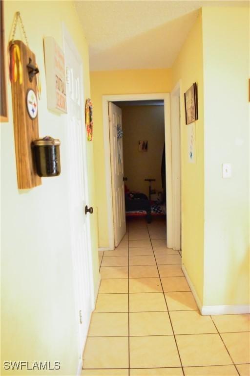 corridor featuring light tile patterned floors and baseboards