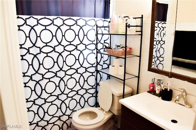 full bathroom featuring toilet, vanity, and tile walls