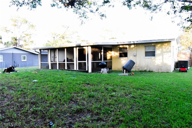 rear view of house with a lawn, a sunroom, and central air condition unit