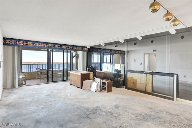 interior space with a water view, concrete floors, and a textured ceiling