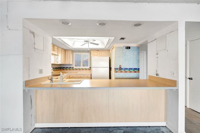 kitchen with white appliances, a tray ceiling, sink, and light brown cabinets