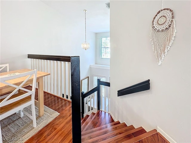 stairs with hardwood / wood-style flooring and a chandelier