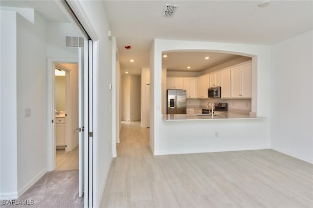 2591 Vine Ave, Naples, FL 34120 - kitchen featuring appliances with stainless steel finishes, white cabinetry, sink, kitchen peninsula, and light wood-type flooring
