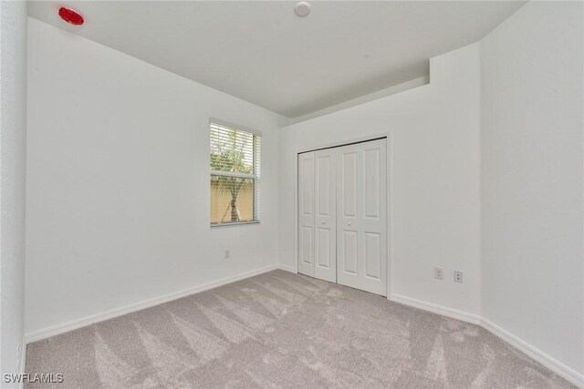 2591 Vine Ave, Naples, FL 34120 - unfurnished bedroom featuring light carpet and a closet