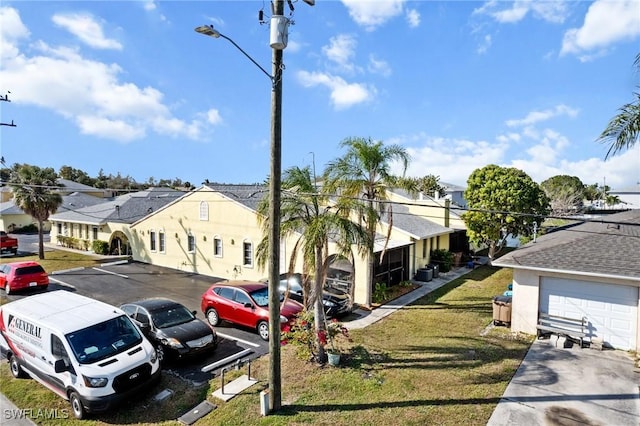 view of front of home with uncovered parking, a shingled roof, a front yard, and a residential view