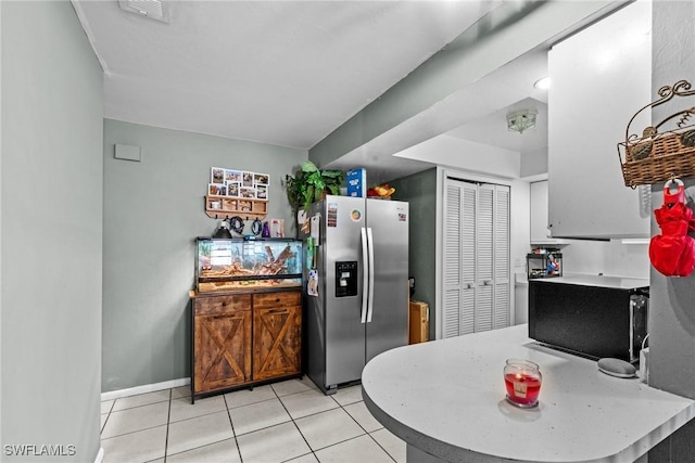 kitchen with baseboards, light countertops, stainless steel fridge with ice dispenser, and light tile patterned flooring