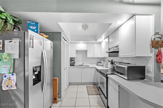 kitchen featuring light tile patterned floors, white cabinets, appliances with stainless steel finishes, light countertops, and under cabinet range hood