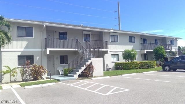 view of property with uncovered parking and stairway