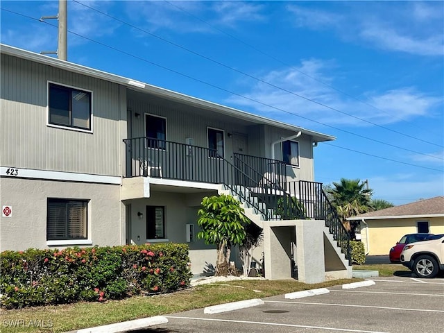 view of property with stairs and uncovered parking