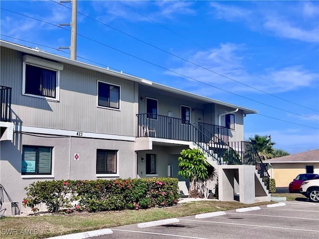 view of property with uncovered parking and stairway