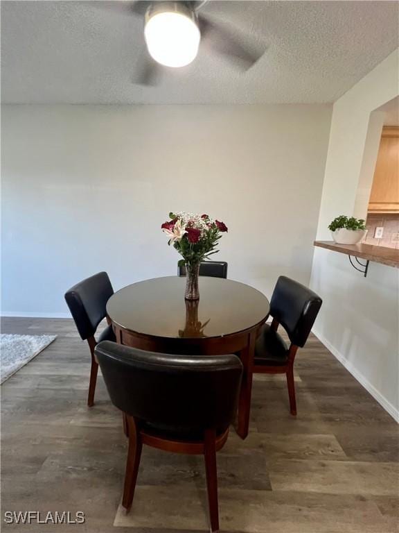 dining space with baseboards, dark wood finished floors, and a textured ceiling