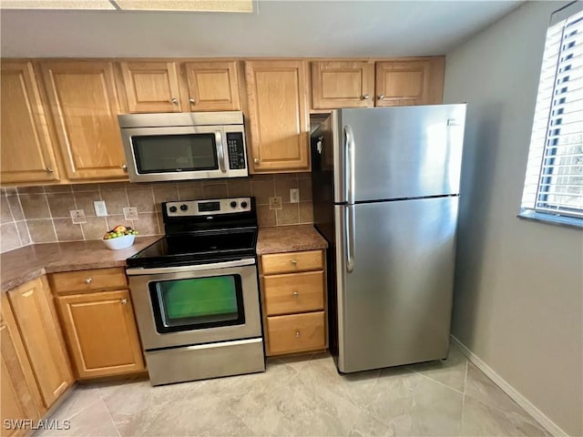 kitchen with tasteful backsplash, baseboards, dark countertops, appliances with stainless steel finishes, and light brown cabinets