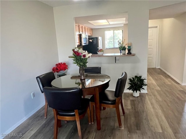 dining area with baseboards and wood finished floors