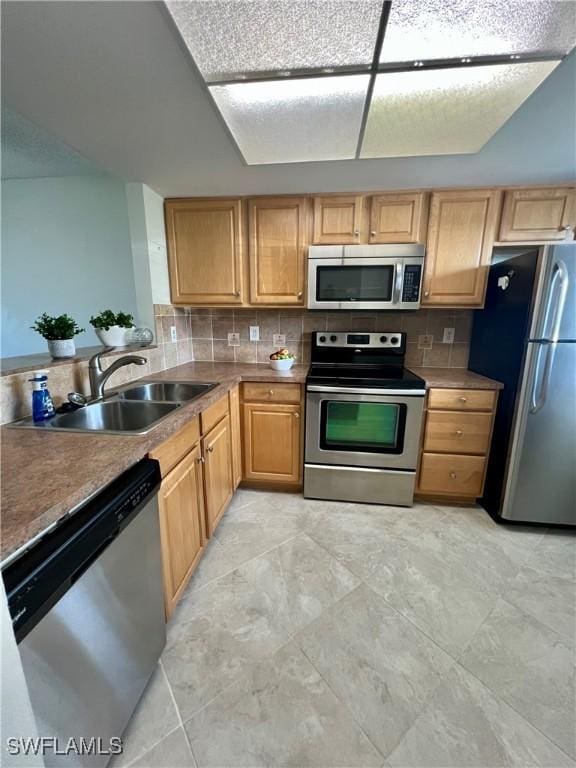 kitchen featuring stainless steel appliances, dark countertops, a sink, and decorative backsplash