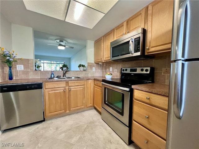 kitchen with ceiling fan, stainless steel appliances, tasteful backsplash, and a sink