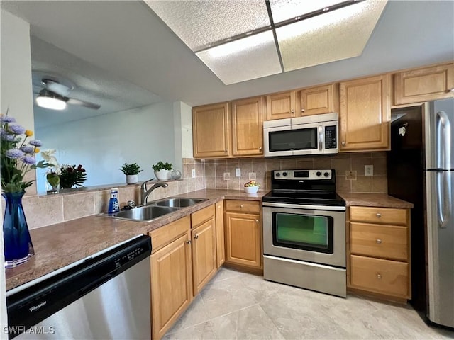 kitchen with ceiling fan, appliances with stainless steel finishes, a sink, and tasteful backsplash