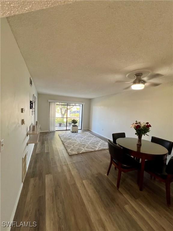 dining room with a textured ceiling, dark wood-style flooring, visible vents, and baseboards