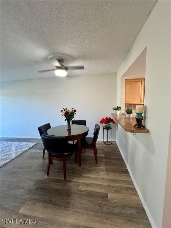 dining room with a textured ceiling, baseboards, and dark wood-style flooring