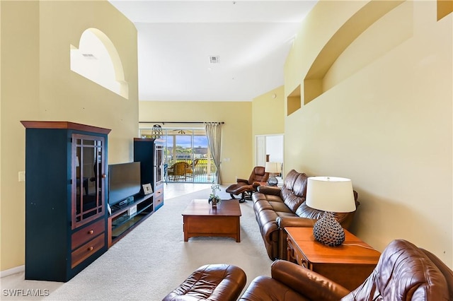 carpeted living room featuring a towering ceiling