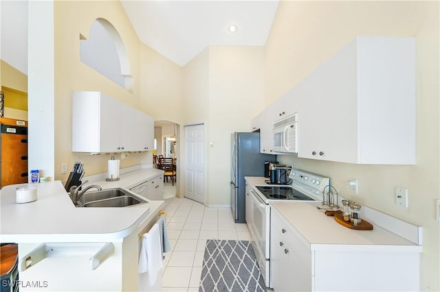 kitchen featuring sink, white appliances, a breakfast bar area, white cabinetry, and kitchen peninsula