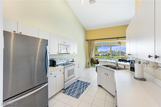 kitchen with high vaulted ceiling, white cabinetry, sink, light tile patterned floors, and white appliances