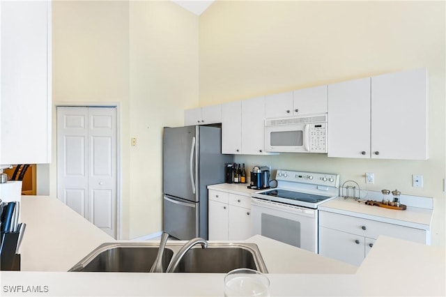 kitchen featuring sink, white appliances, white cabinets, and a high ceiling