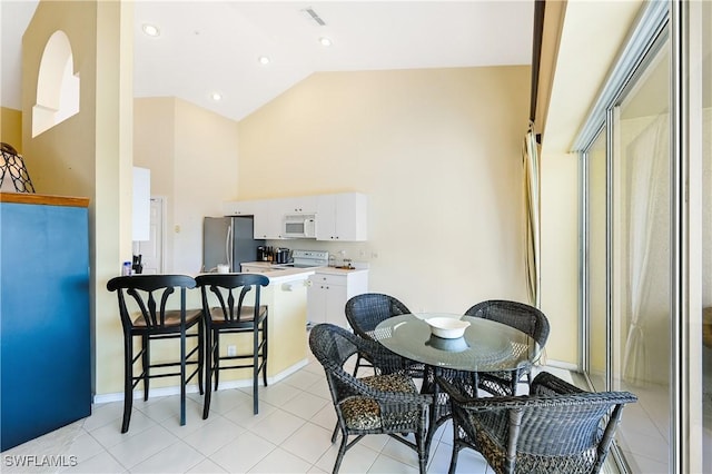 dining area featuring light tile patterned floors and high vaulted ceiling