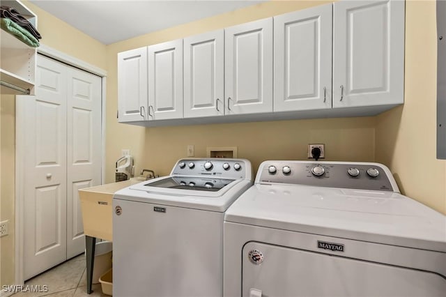 washroom featuring separate washer and dryer, light tile patterned floors, and cabinets