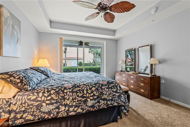 carpeted bedroom featuring access to exterior, a raised ceiling, and ceiling fan