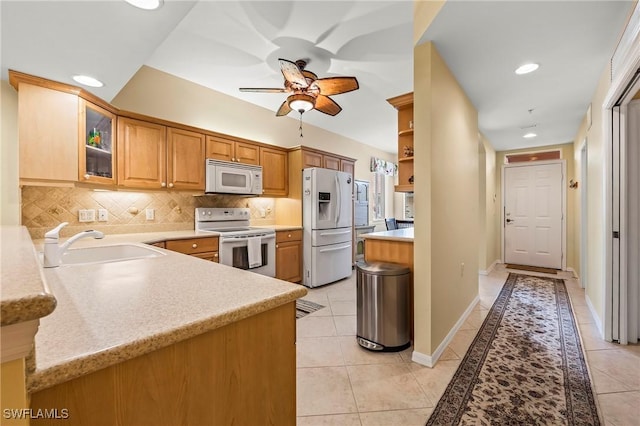 kitchen with light tile patterned flooring, sink, kitchen peninsula, white appliances, and decorative backsplash