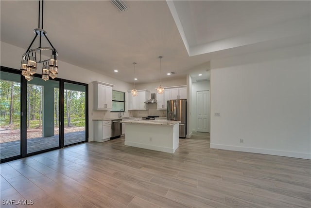 kitchen featuring hanging light fixtures, a center island, white cabinets, and appliances with stainless steel finishes