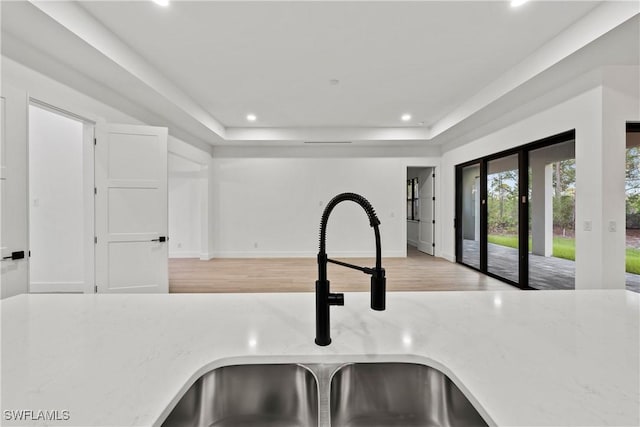 kitchen featuring a raised ceiling, sink, and light hardwood / wood-style floors