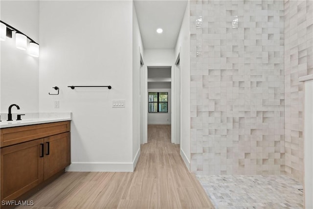 bathroom featuring vanity, wood-type flooring, and a tile shower