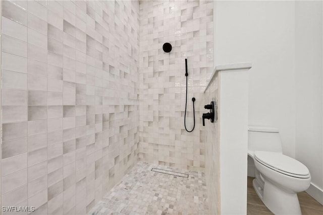 bathroom featuring tiled shower and toilet