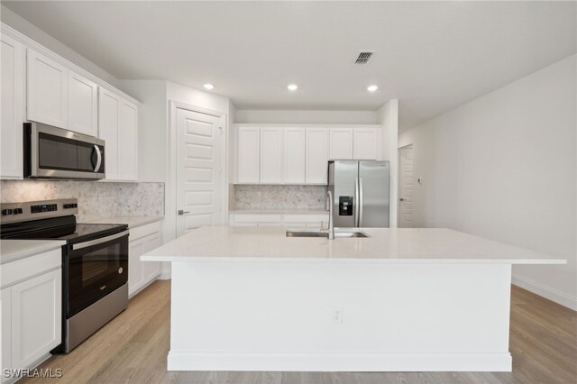 kitchen with sink, an island with sink, white cabinets, and appliances with stainless steel finishes